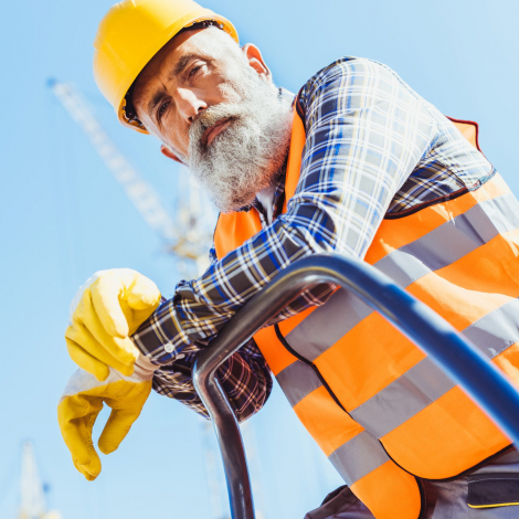 Bearded construction worker in reflective vest and hardhat leaning on guardrail